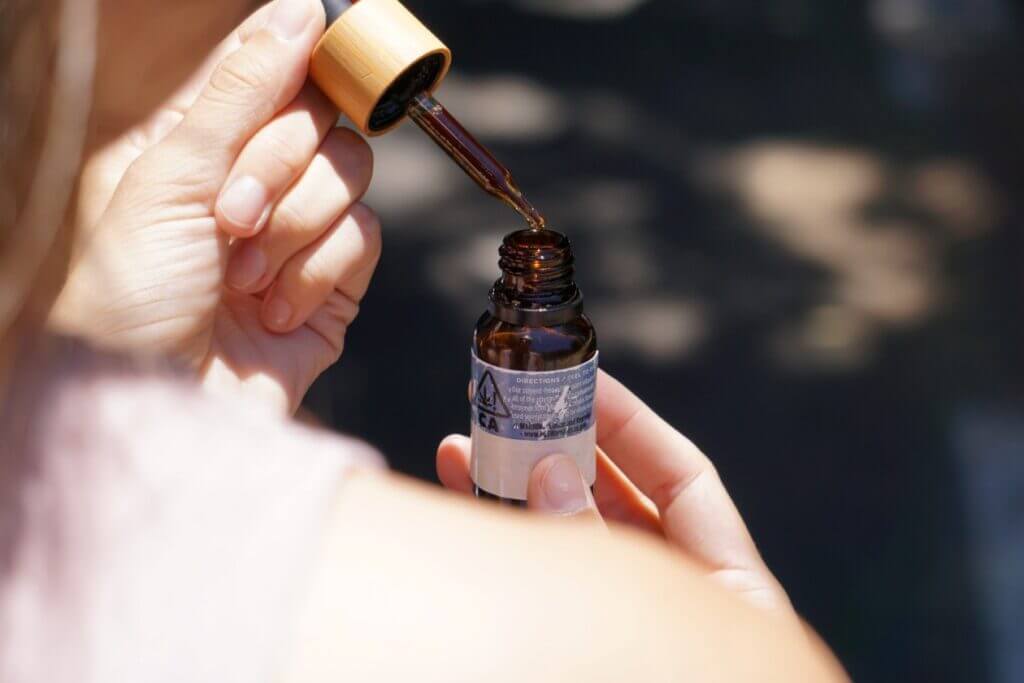 A woman holding a bottle of CBD oil and a dropper